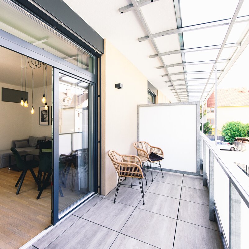Überdachter Balkon mit Rattanstühlen – 2-Zimmer Wohnung, Kurzzeitmiete Graz, Wohnen auf Zeit für 1 bis 6 Monate