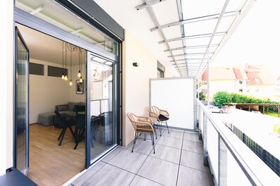 Überdachter Balkon mit Rattanstühlen – 2-Zimmer Wohnung, Kurzzeitmiete Graz, Wohnen auf Zeit für 1 bis 6 Monate
