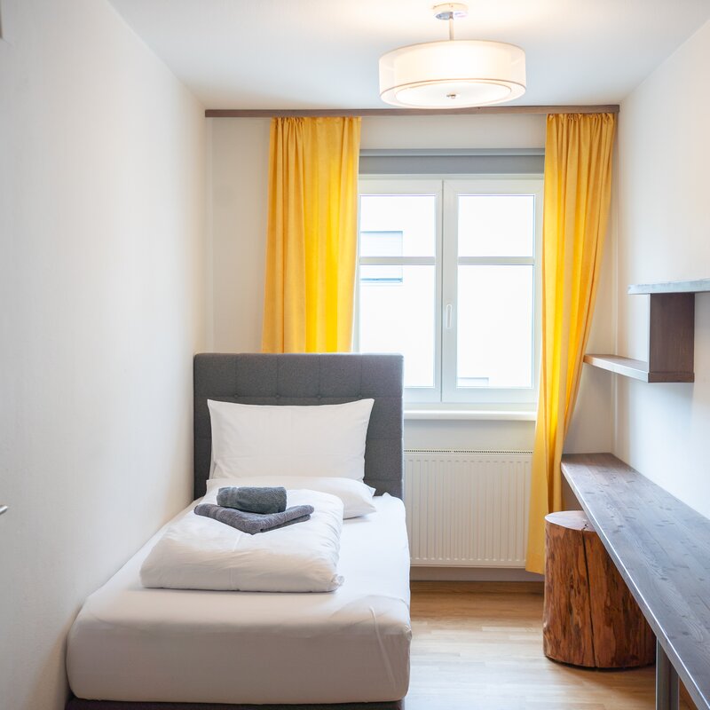 Helles 1-Zimmer Apartment, möbliert mit Schreibtisch & gelben Akzenten – Kurzzeitmiete & Wohnen auf Zeit für 1 bis 6 Monate in Graz