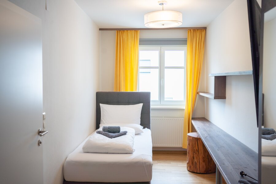 Helles 1-Zimmer Apartment, möbliert mit Schreibtisch & gelben Akzenten – Kurzzeitmiete & Wohnen auf Zeit für 1 bis 6 Monate in Graz