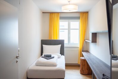 Helles 1-Zimmer Apartment, möbliert mit Schreibtisch & gelben Akzenten – Kurzzeitmiete & Wohnen auf Zeit für 1 bis 6 Monate in Graz