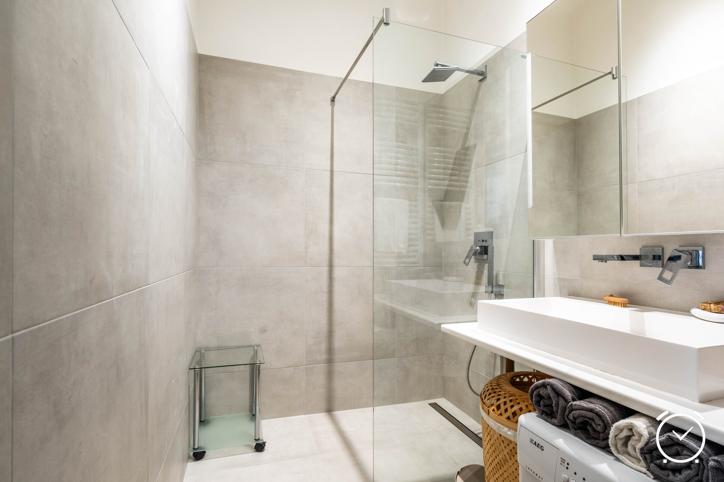 Im keinen, aber top ausgestattetem Badezimmer mit begehbarer Regendusche. Ein großer Spiegelkasten mit Platz für Pflegeprodukte (erste Grundausstattung ist vorhanden), einem großem Waschbecken und einer Waschmaschine 