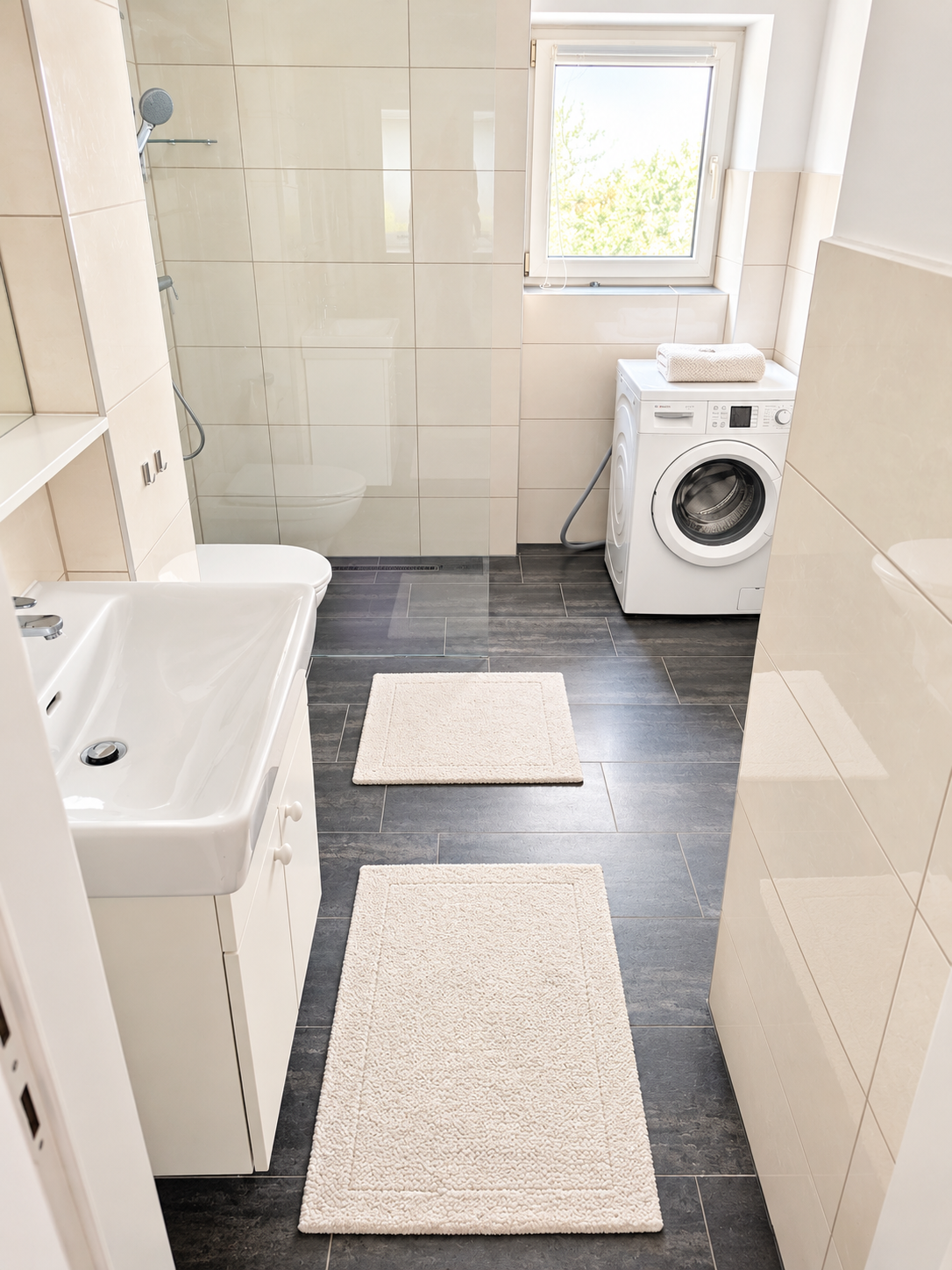 Das gepflegte Badezimmer ist hell und freundlich gestaltet und verfügt über Dusche, Waschbecken, WC und Waschmaschine.
