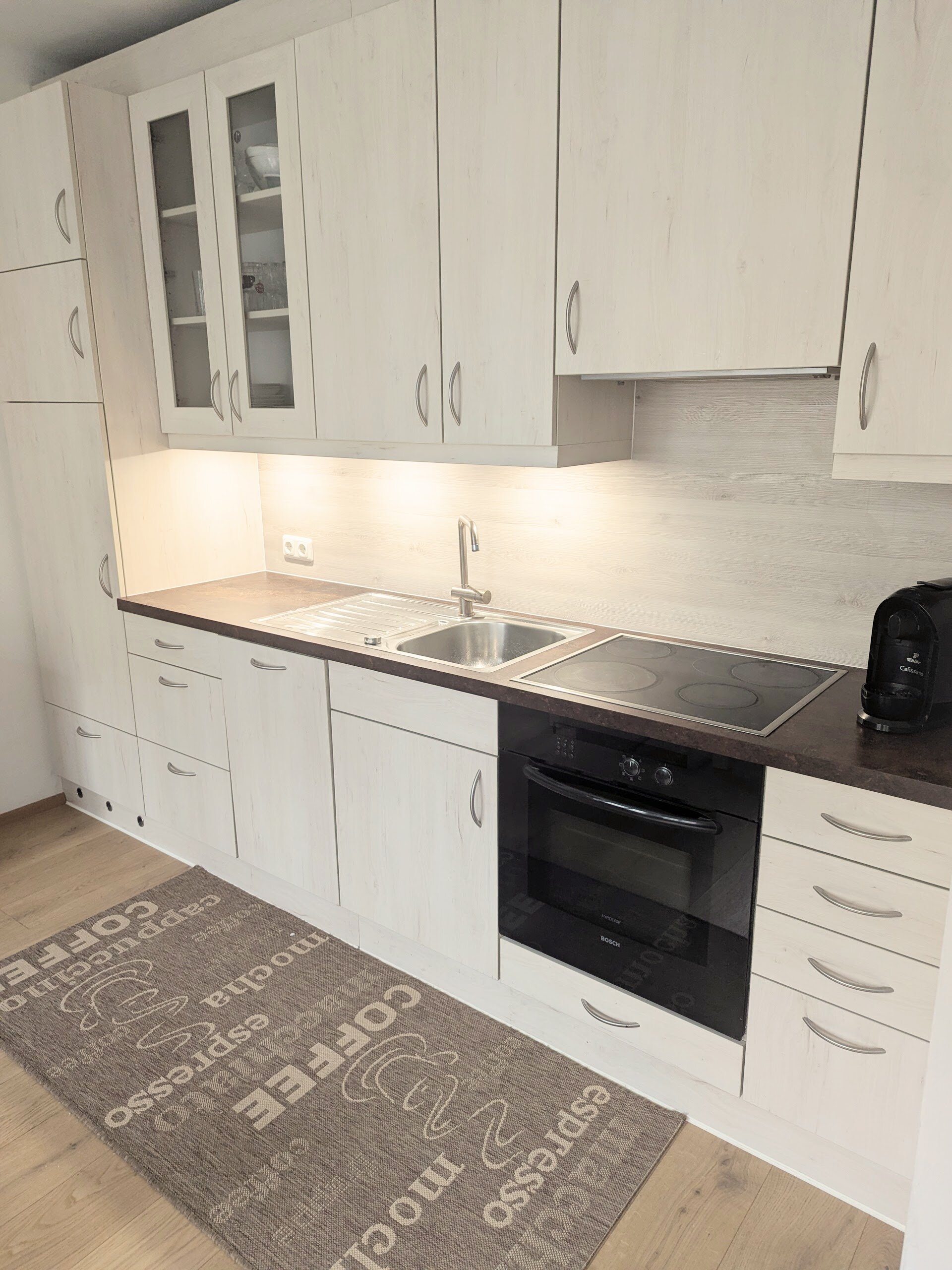 Küchenzeile mit Herd und Backofen, Kühlschrank mit Gefrierfach, Kaffeemaschine mit Tabs