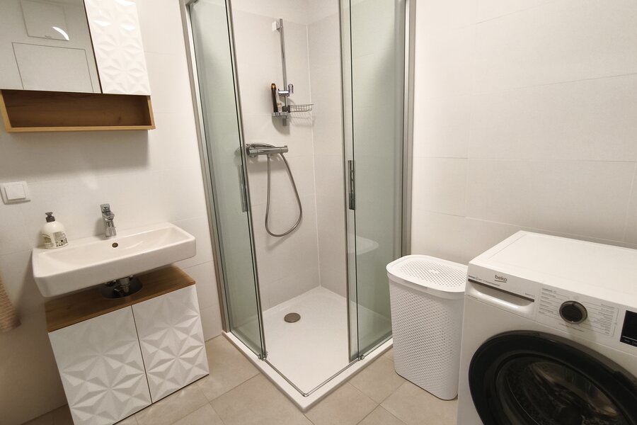 Modern ausgestattetes Badezimmer mit Dusche, Waschmaschine und praktischer Raumaufteilung. | © Greta Stoyanova