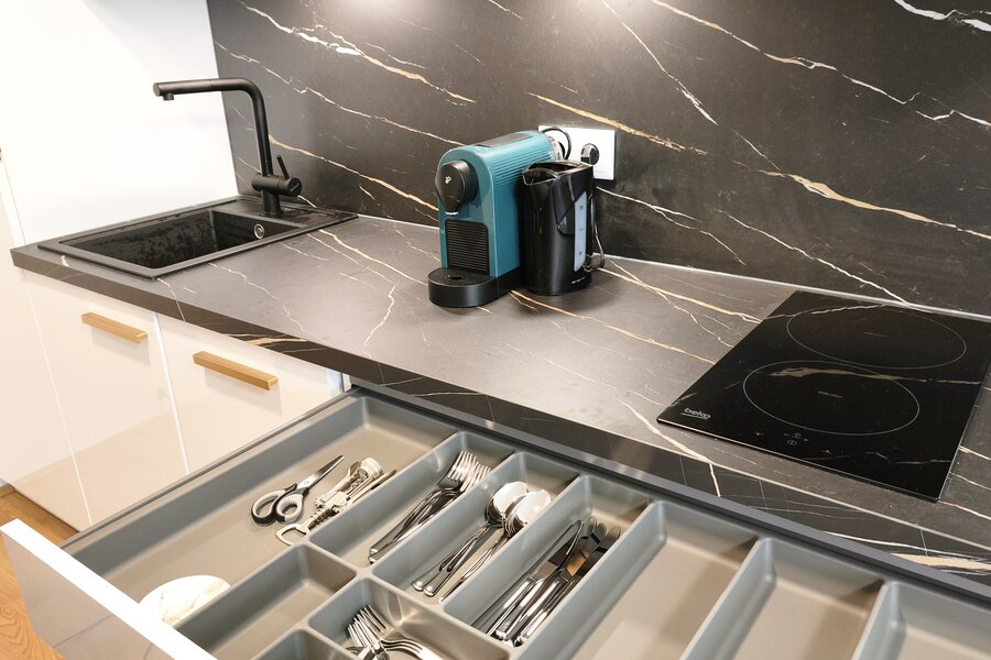 Detailansicht der Küche mit vollständiger Ausstattung inklusive Kochfeld, Kaffeemaschine und Küchenutensilien. | © Greta Stoyanova