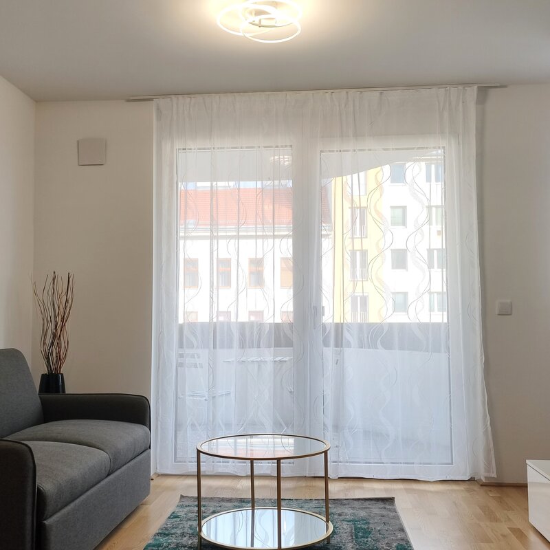 Heller Wohnbereich mit großen Fensterflächen und direktem Zugang zum Balkon – modern eingerichtet und einladend. | © Greta Stoyanova