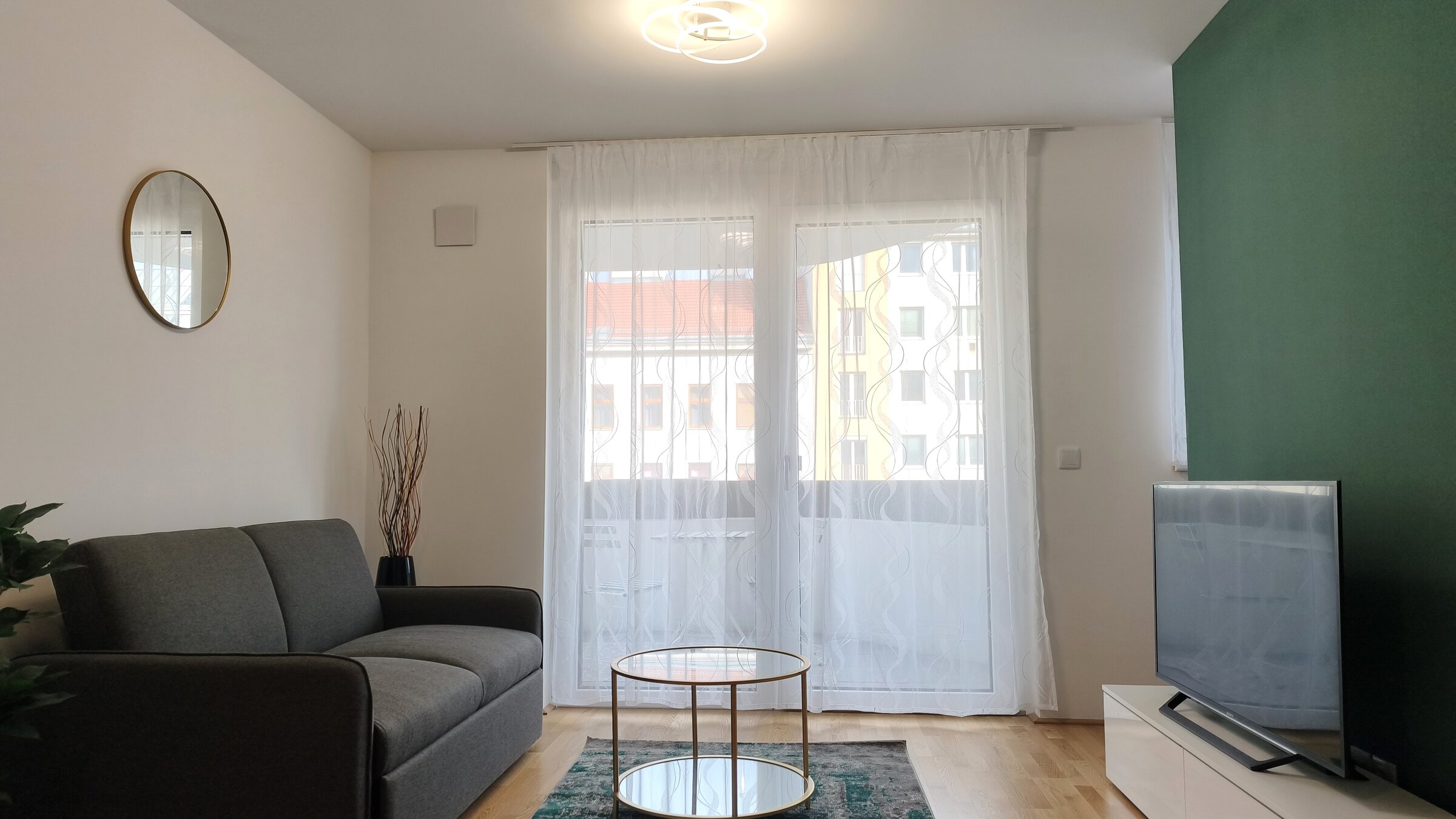 Heller Wohnbereich mit großen Fensterflächen und direktem Zugang zum Balkon – modern eingerichtet und einladend. | © Greta Stoyanova