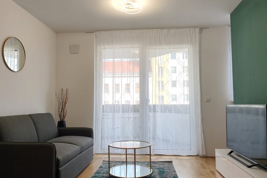 Heller Wohnbereich mit großen Fensterflächen und direktem Zugang zum Balkon – modern eingerichtet und einladend. | © Greta Stoyanova