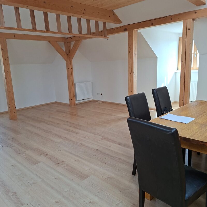 Helles Wohnzimmer mit Holzbalken & Esstisch – 1-Zimmer Wohnung, Kurzzeitmiete & Wohnen auf Zeit 1–6 Monate, Anthering