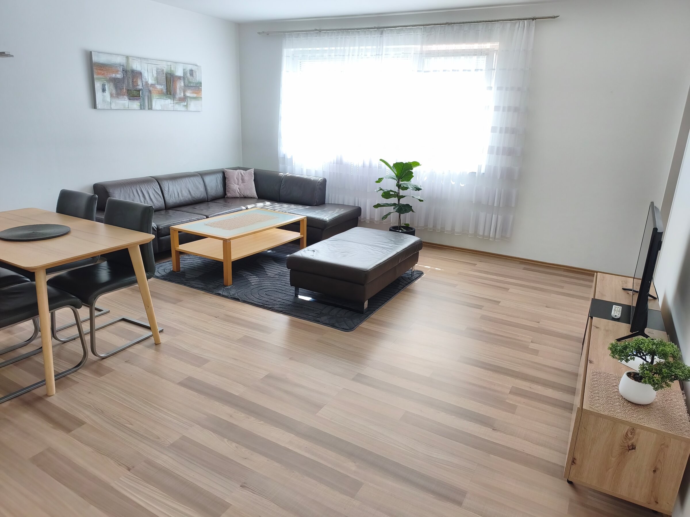 Bright living room with leather sofa & dining area – 4-room apartment, short-term rental & temporary housing for 1 to 6 months in Linz
