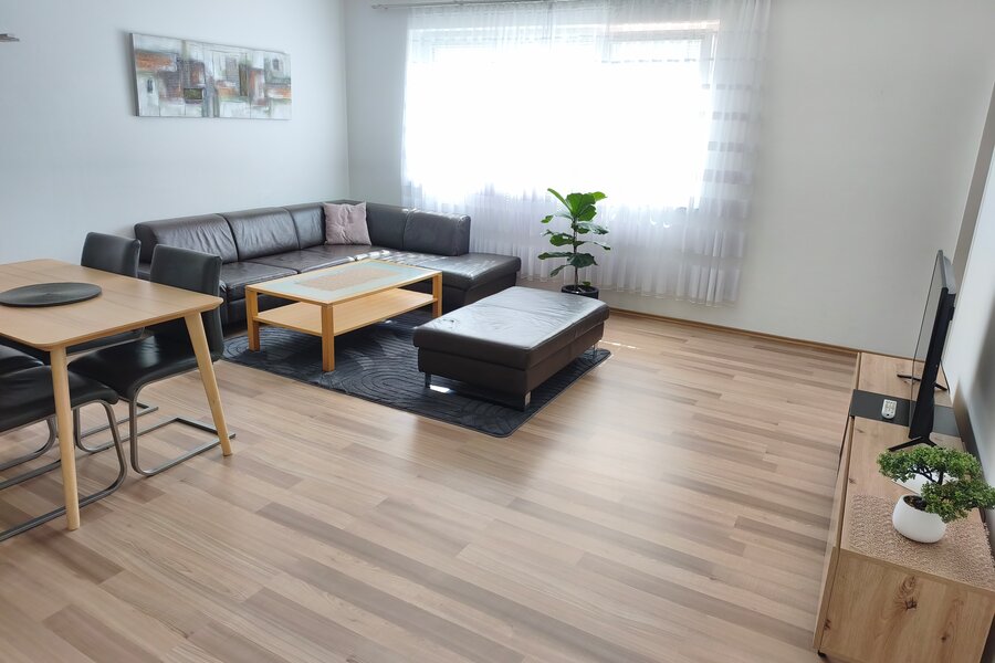 Bright living room with leather sofa & dining area – 4-room apartment, short-term rental & temporary housing for 1 to 6 months in Linz