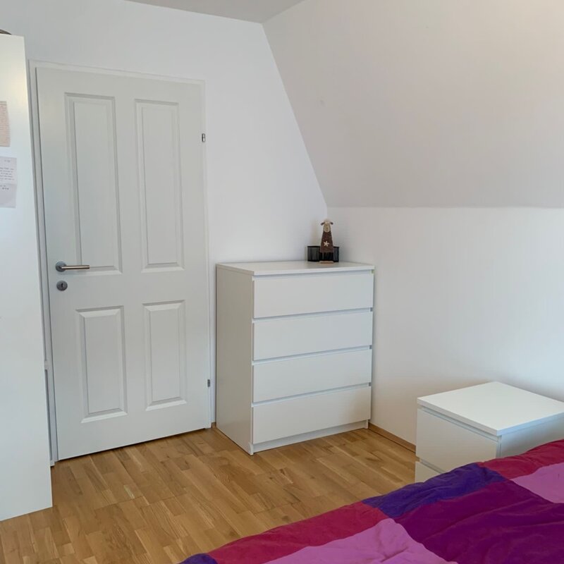 A chest of drawers is located on the right, a shelving unit on the left, and an additional spacious wardrobe is available just outside the room.