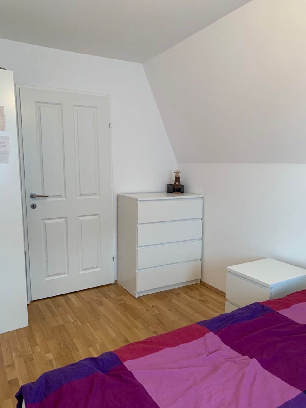 A chest of drawers is located on the right, a shelving unit on the left, and an additional spacious wardrobe is available just outside the room.