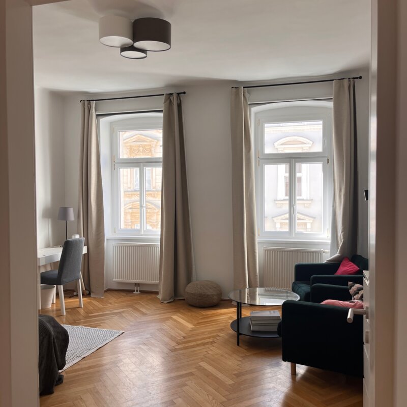 Helles Wohnzimmer mit Parkettboden & großen Fenstern – 1-Zimmer Wohnung zur Kurzzeitmiete in Wien