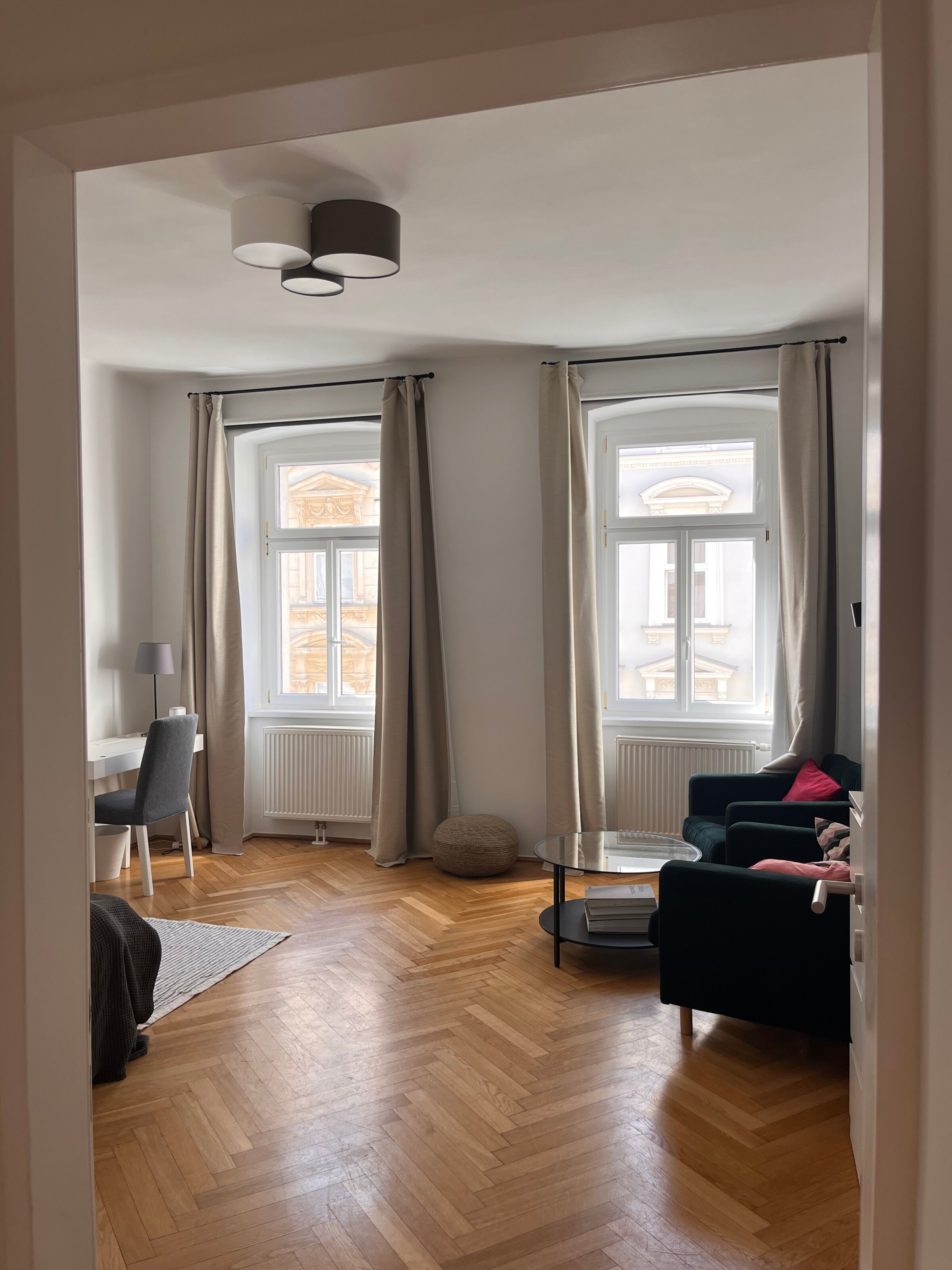 Helles Wohnzimmer mit Parkettboden & großen Fenstern – 1-Zimmer Wohnung zur Kurzzeitmiete in Wien