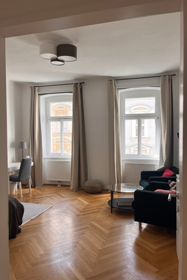 Helles Wohnzimmer mit Parkettboden & großen Fenstern – 1-Zimmer Wohnung zur Kurzzeitmiete in Wien
