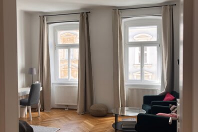 Helles Wohnzimmer mit Parkettboden & großen Fenstern – 1-Zimmer Wohnung zur Kurzzeitmiete in Wien