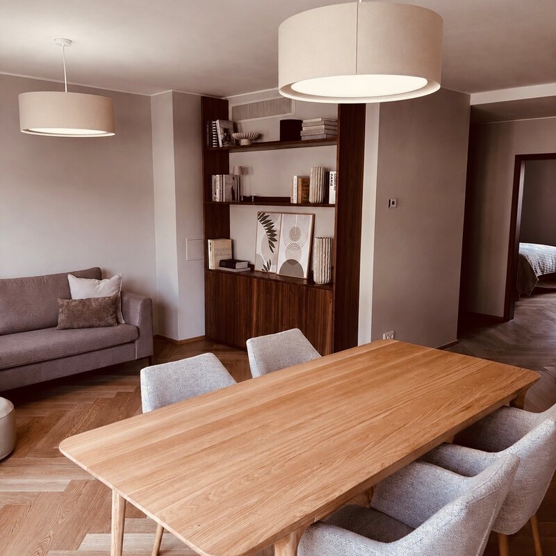 Der lichtdurchflutete Wohn- und Essbereich verbindet hochwertige Materialien, warmes Holz, modernes Interior und eine durchdachte Raumaufteilung. Sofa, Essbereich und massgefertigtes Regal schaffen eine ruhige, stilvolle und sehr behagliche Wohnatmosphäre.