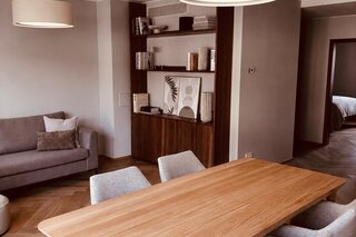 Der lichtdurchflutete Wohn- und Essbereich verbindet hochwertige Materialien, warmes Holz, modernes Interior und eine durchdachte Raumaufteilung. Sofa, Essbereich und massgefertigtes Regal schaffen eine ruhige, stilvolle und sehr behagliche Wohnatmosphäre.