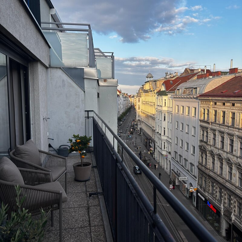 Von der Terrasse blickt man entlang der Josefstädter Straße Richtung Innenstadt. Die Josefstädter Straße verbindet urbanen Charme mit hoher Lebensqualität und bietet zahlreiche Restaurants, Cafés, Boutiquen und Geschäfte. Sie führt direkt zur Ringstraße sowie weiter zum Volksgarten und zur Hofburg.