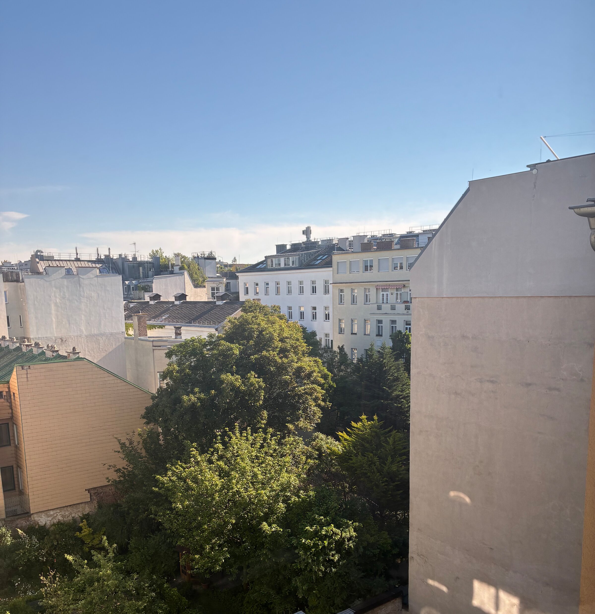 Vom größeren Schlafzimmer blickt man über die begrünten Innenhöfe, die dem Raum eine besonders ruhige und angenehme Atmosphäre verleihen. Der Ausblick ins Grüne unterstreicht den wohnlichen Charakter und die geschützte Lage der Schlafzimmer.