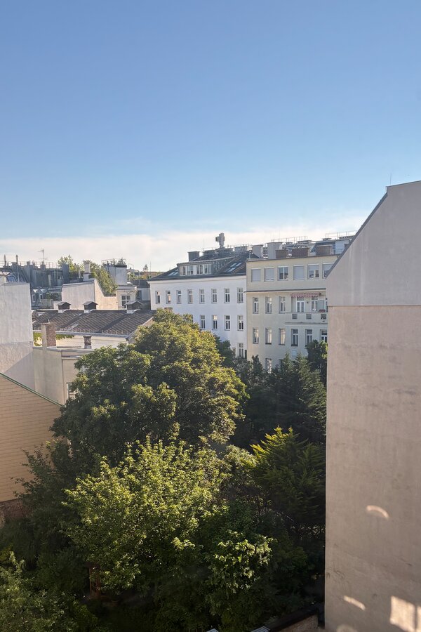 Vom größeren Schlafzimmer blickt man über die begrünten Innenhöfe, die dem Raum eine besonders ruhige und angenehme Atmosphäre verleihen. Der Ausblick ins Grüne unterstreicht den wohnlichen Charakter und die geschützte Lage der Schlafzimmer.