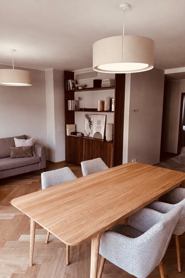 Der lichtdurchflutete Wohn- und Essbereich verbindet hochwertige Materialien, warmes Holz, modernes Interior und eine durchdachte Raumaufteilung. Sofa, Essbereich und massgefertigtes Regal schaffen eine ruhige, stilvolle und sehr behagliche Wohnatmosphäre.