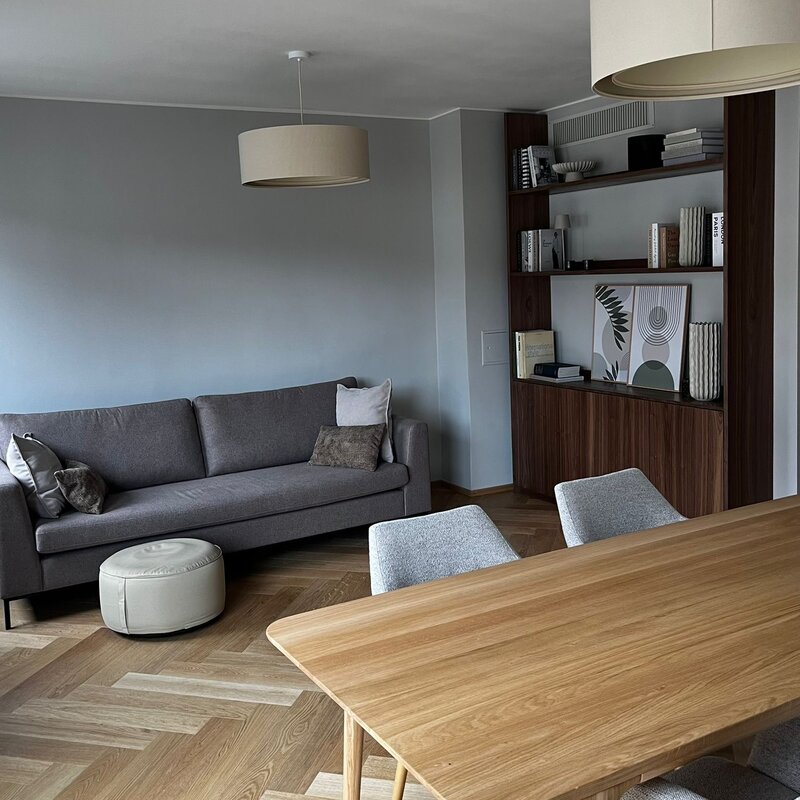 Der lichtdurchflutete Wohn- und Essbereich verbindet hochwertige Materialien, warmes Holz, modernes Interior und eine durchdachte Raumaufteilung. Sofa, Essbereich und massgefertigtes Regal schaffen eine ruhige, stilvolle und sehr behagliche Wohnatmosphäre.