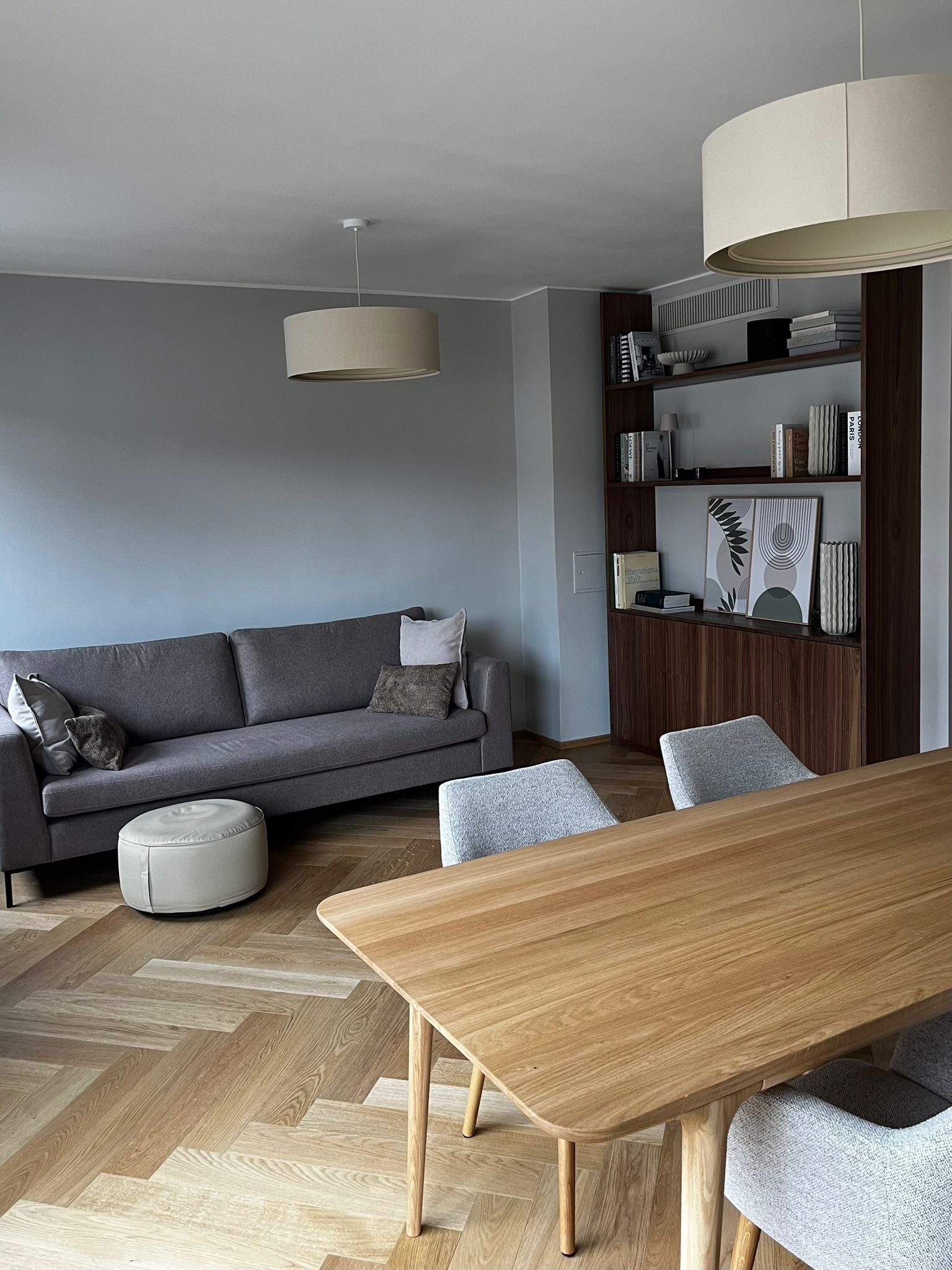 Der lichtdurchflutete Wohn- und Essbereich verbindet hochwertige Materialien, warmes Holz, modernes Interior und eine durchdachte Raumaufteilung. Sofa, Essbereich und massgefertigtes Regal schaffen eine ruhige, stilvolle und sehr behagliche Wohnatmosphäre.