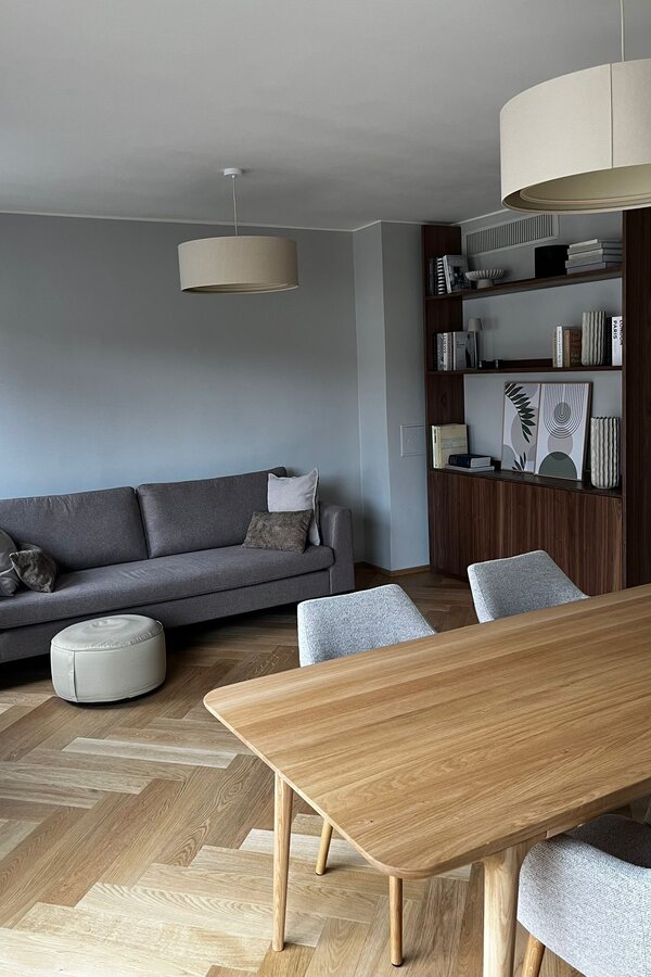 Der lichtdurchflutete Wohn- und Essbereich verbindet hochwertige Materialien, warmes Holz, modernes Interior und eine durchdachte Raumaufteilung. Sofa, Essbereich und massgefertigtes Regal schaffen eine ruhige, stilvolle und sehr behagliche Wohnatmosphäre.