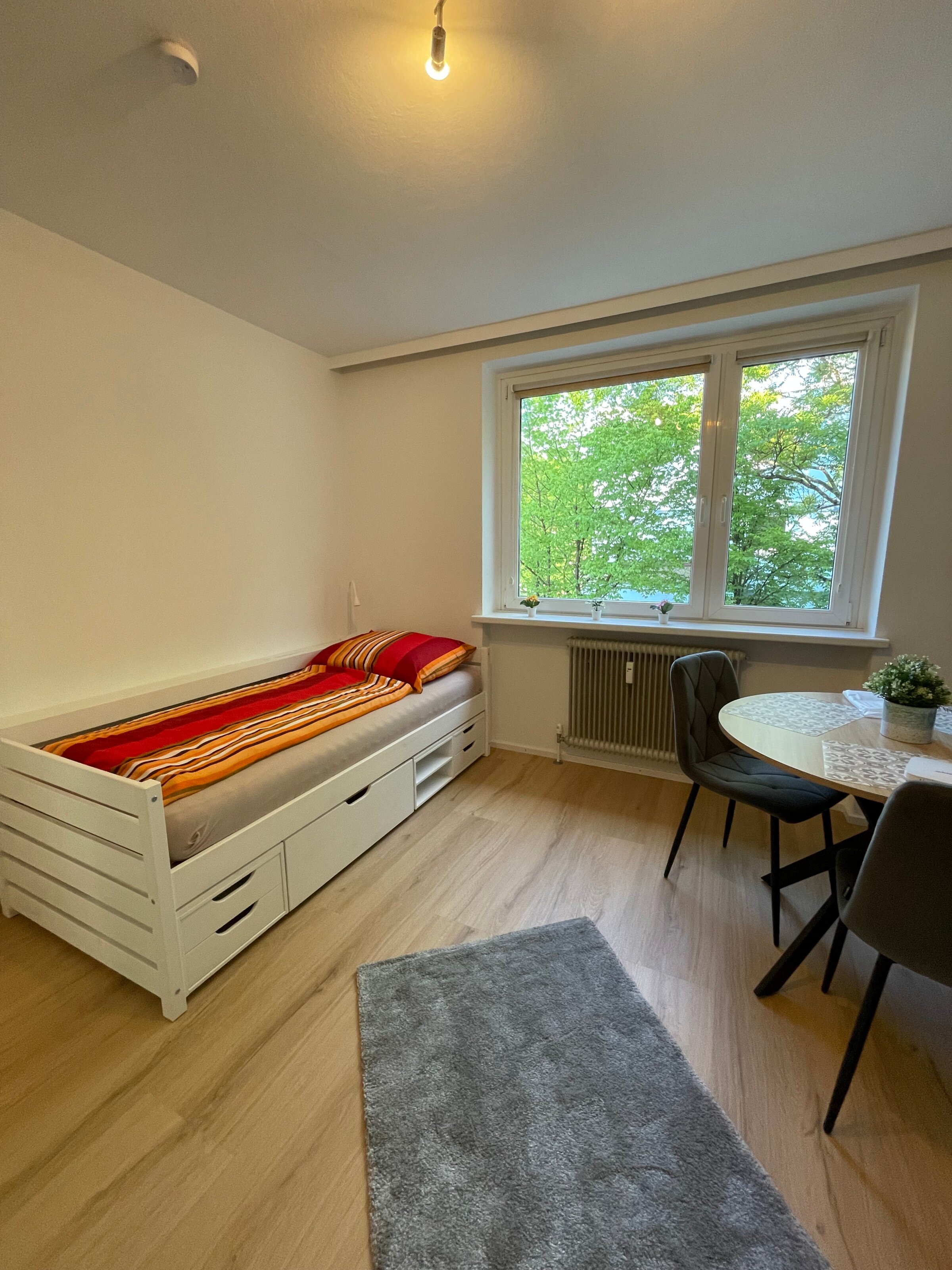 Wohnzimmer mit Bett, Tisch und Fensterfront in Salzburg Süd | © Sonja Hana