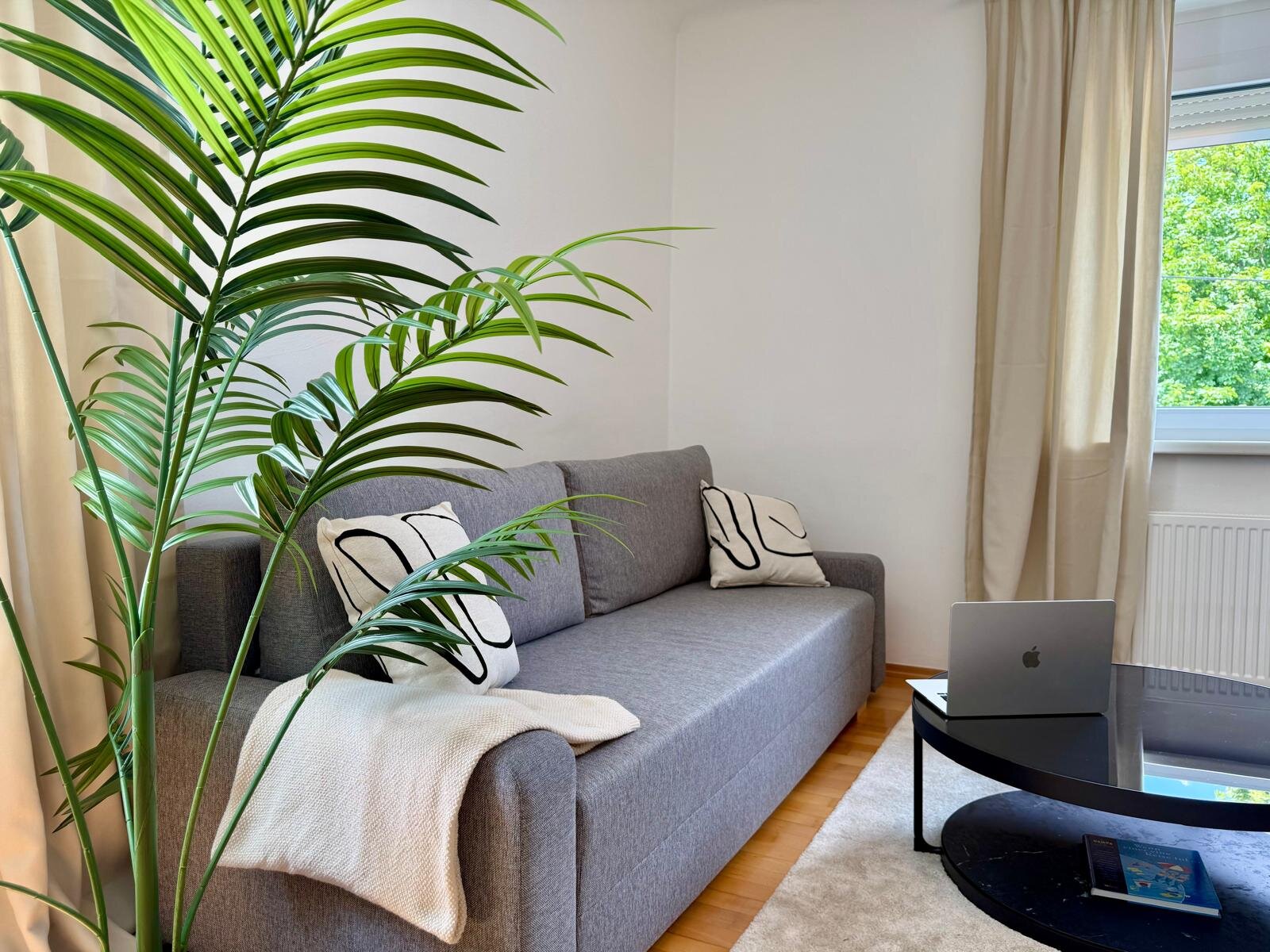 Helles Wohnzimmer mit Sofa & Grünpflanze – 3-Zimmer Wohnung, Kurzzeitmiete & Wohnen auf Zeit für 1 bis 6 Monate in Graz