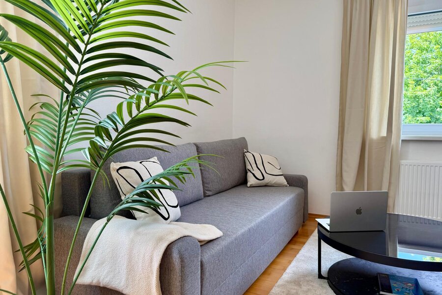 Helles Wohnzimmer mit Sofa & Grünpflanze – 3-Zimmer Wohnung, Kurzzeitmiete & Wohnen auf Zeit für 1 bis 6 Monate in Graz