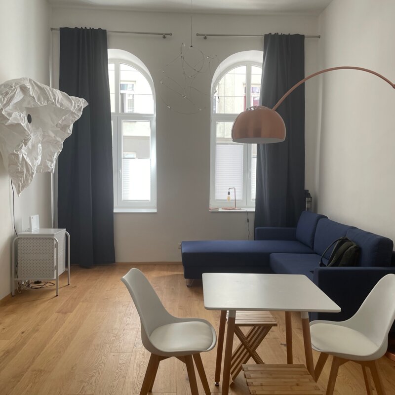 Bright studio with designer furniture, blue sofa & wood floor – 1-room apartment for short-term rental Vienna