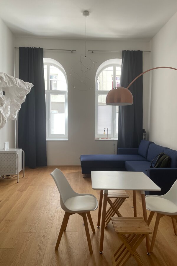 Bright studio with designer furniture, blue sofa & wood floor – 1-room apartment for short-term rental Vienna