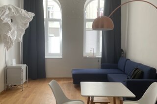 Bright studio with designer furniture, blue sofa & wood floor – 1-room apartment for short-term rental Vienna