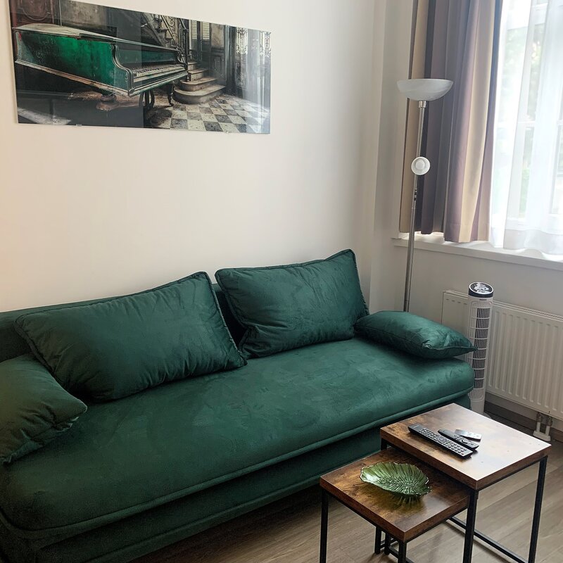 Furnished 1-room apartment with green velvet sofa – short-term rental Vienna, temporary housing for 1 to 6 months.