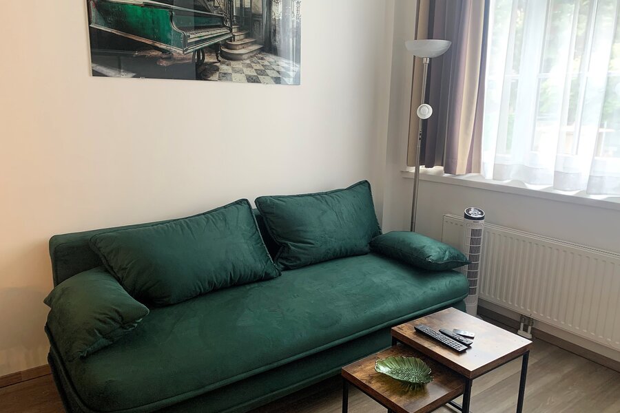 Furnished 1-room apartment with green velvet sofa – short-term rental Vienna, temporary housing for 1 to 6 months.