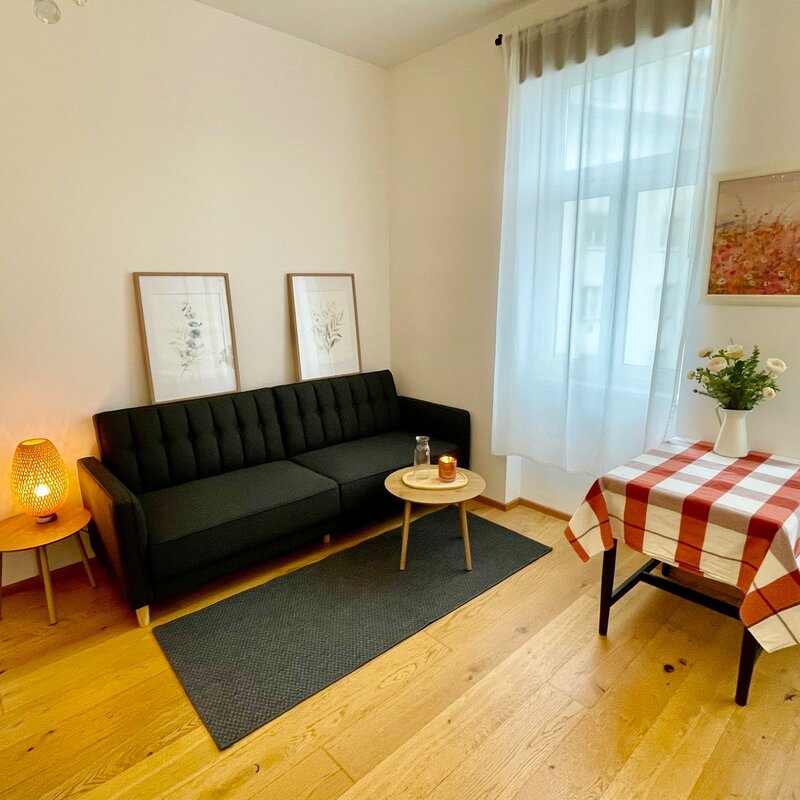 Bright living room with sofa & table – 1-room apartment, short-term rental Vienna, temporary housing for 1 to 6 months.