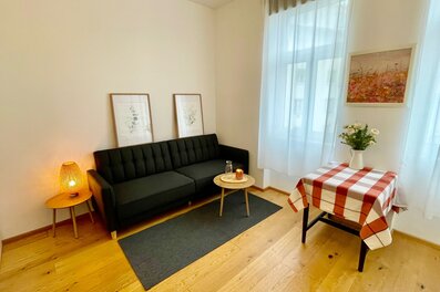 Bright living room with sofa & table – 1-room apartment, short-term rental Vienna, temporary housing for 1 to 6 months.