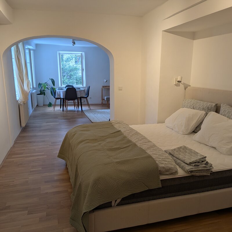 Ein eleganter Schlafbereich mit warmen Texturen, der durch den charakteristischen Torbogen einen offenen Blick in den Wohnraum bietet. | © Vermieter