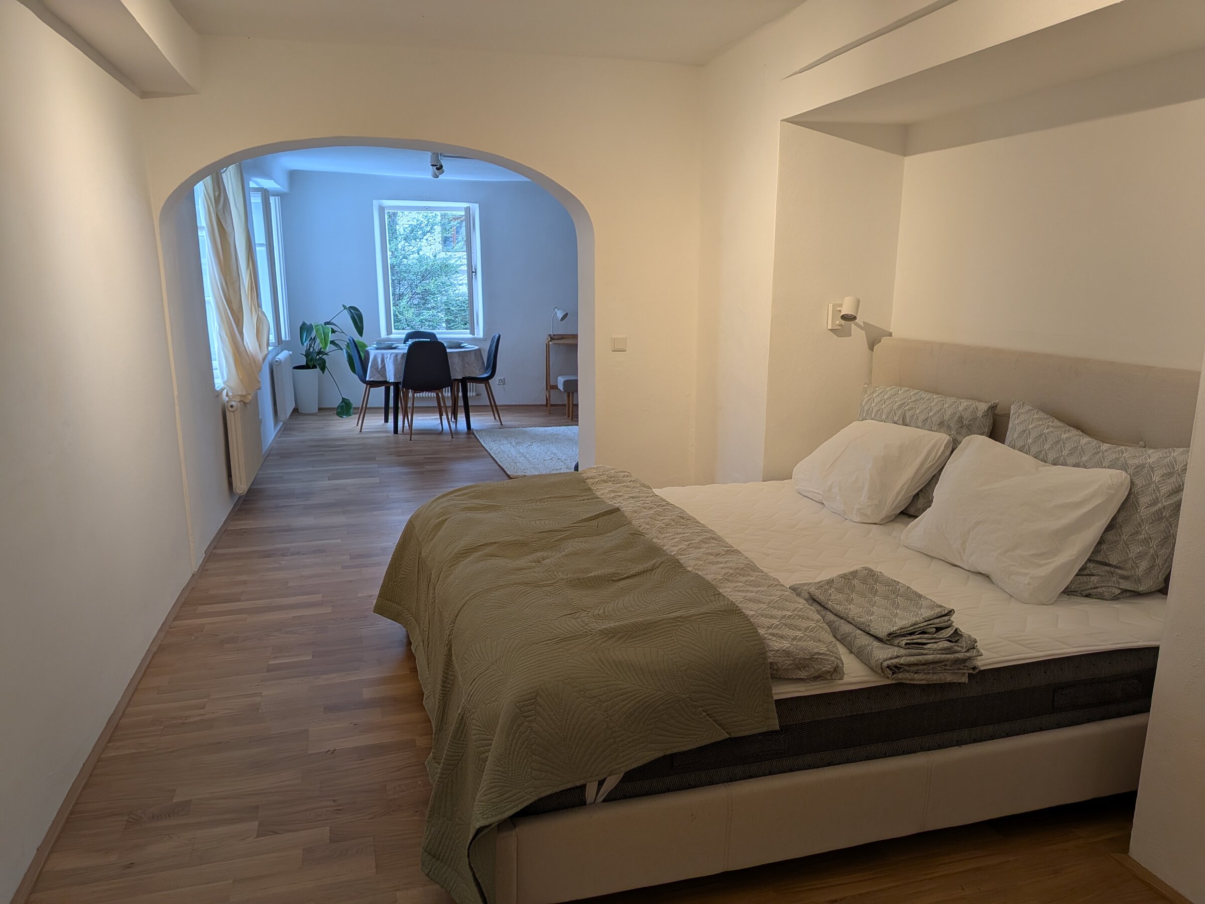Ein eleganter Schlafbereich mit warmen Texturen, der durch den charakteristischen Torbogen einen offenen Blick in den Wohnraum bietet. | © Vermieter