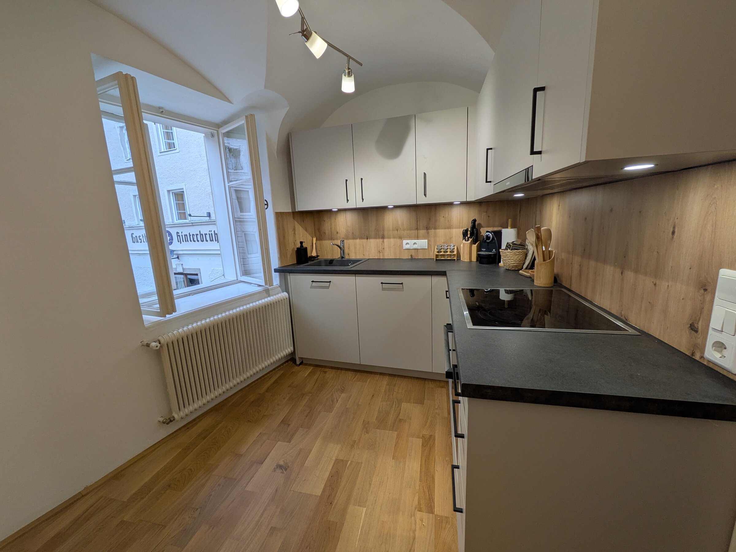 Eine hochwertige Küche mit warmen Holzelementen, modernen Geräten und viel Tageslicht – perfekt für kulinarische Momente im Herzen der Stadt.