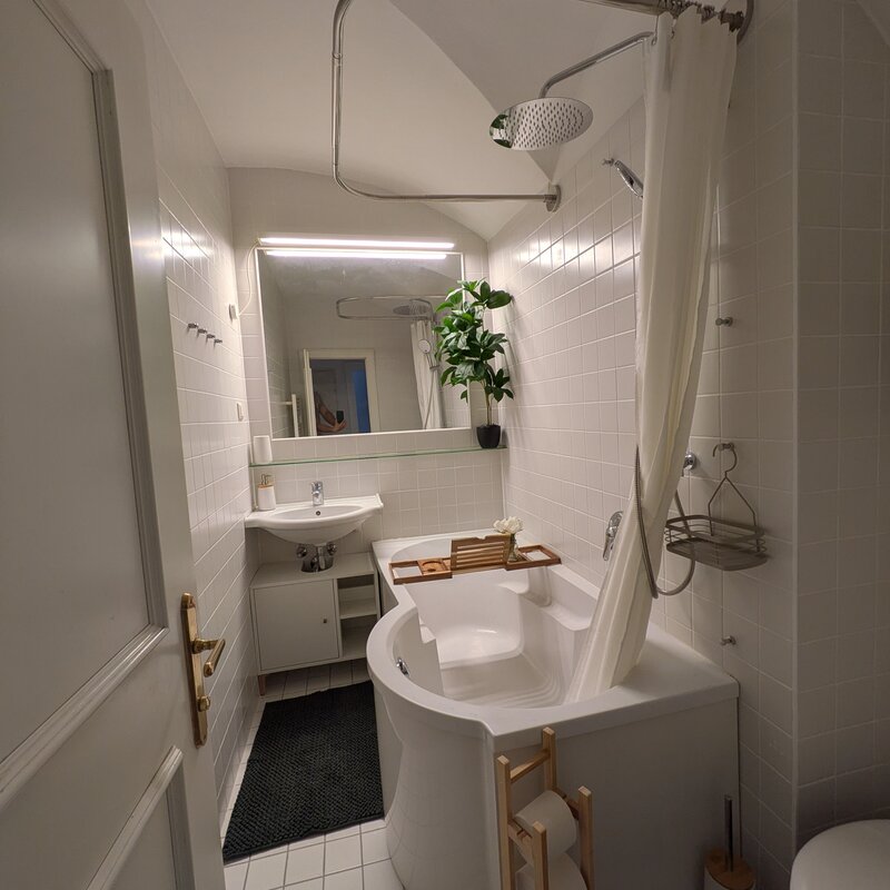 Ein helles, modern gestaltetes Badezimmer mit Badewanne, großen Spiegeln und warmen Holzdetails – stilvoll, gepflegt und perfekt für entspannte Momente. | © Vermieter