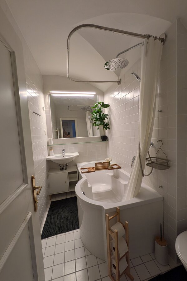 Ein helles, modern gestaltetes Badezimmer mit Badewanne, großen Spiegeln und warmen Holzdetails – stilvoll, gepflegt und perfekt für entspannte Momente. | © Vermieter