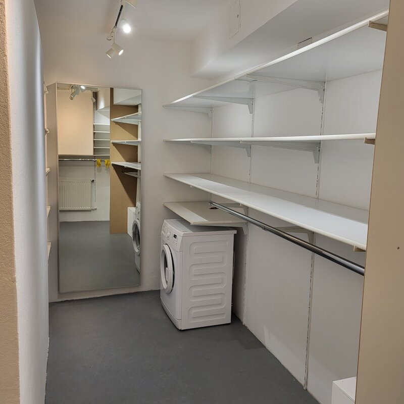 Ein großzügiger, klar strukturierter begehbarer Schrank mit offenen Regalen, großem Spiegel und integrierter Waschmöglichkeit – praktisch, modern und perfekt organisiert. | © Vermieter