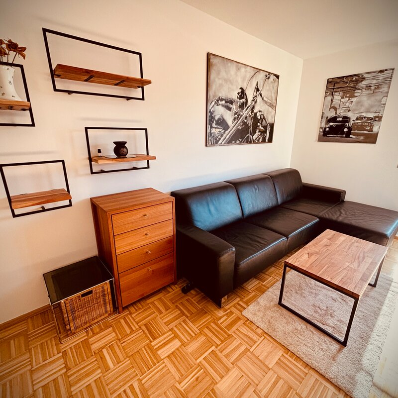 Möbliertes Wohnzimmer mit Ledersofa & Holzelementen – 1-Zimmer Apartment zur Kurzzeitmiete, Wohnen auf Zeit 1 bis 6 Monate, Graz | © PP