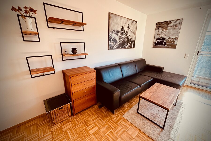 Möbliertes Wohnzimmer mit Ledersofa & Holzelementen – 1-Zimmer Apartment zur Kurzzeitmiete, Wohnen auf Zeit 1 bis 6 Monate, Graz | © PP