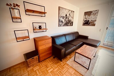 Möbliertes Wohnzimmer mit Ledersofa & Holzelementen – 1-Zimmer Apartment zur Kurzzeitmiete, Wohnen auf Zeit 1 bis 6 Monate, Graz | © PP